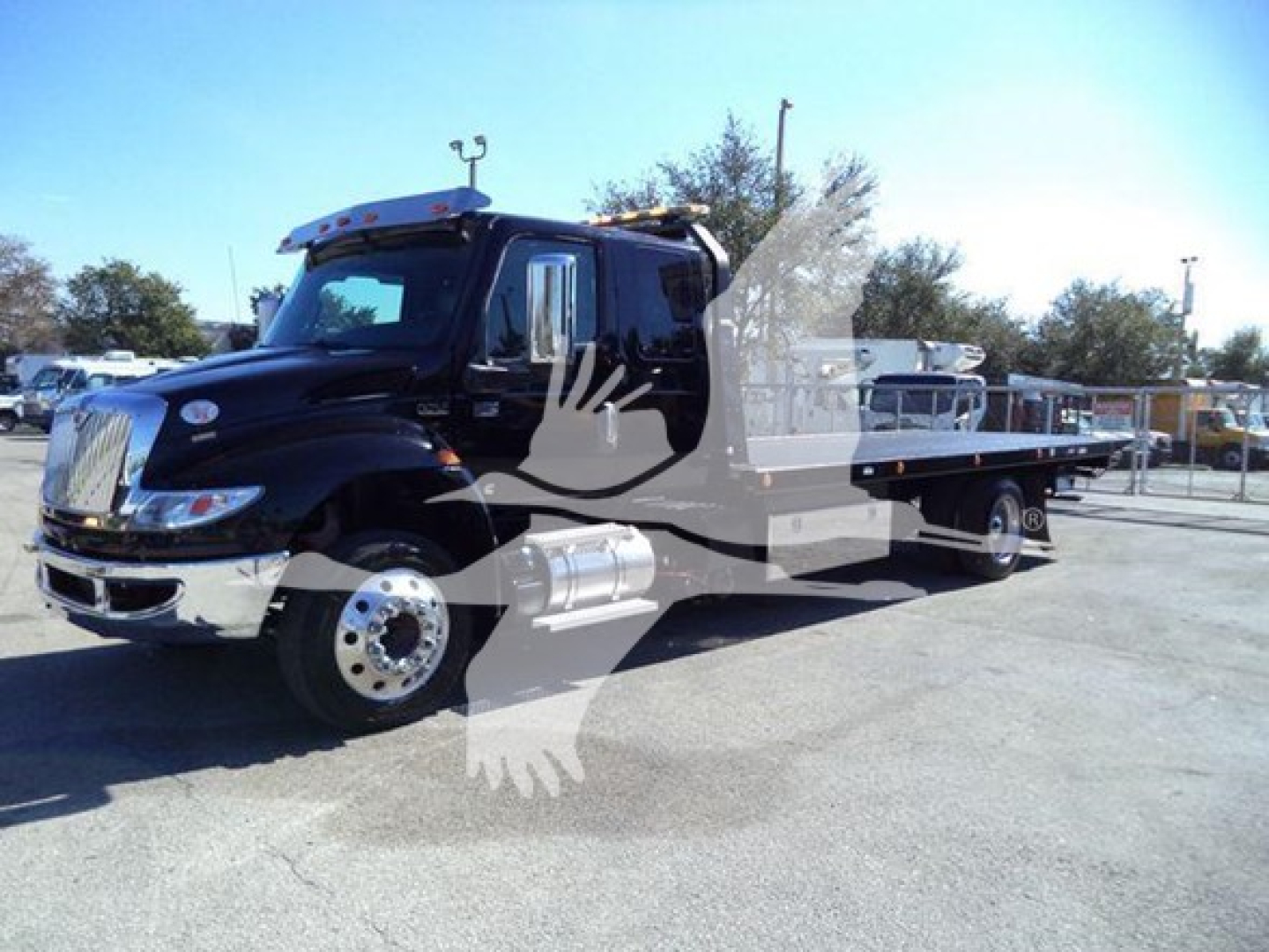 International MV rollback truck in black, side view, flatbed with dual rear axles and chrome fuel tanks.
