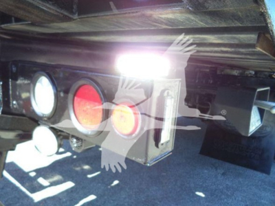 Truck hitch area showing rear lights and hitch components under plyboard bed