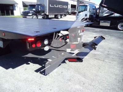 Truck rollback bed with rear platform and hydraulic ramps visible, taillights and hitch area in view.