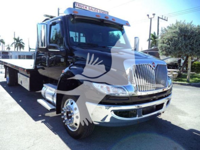 Truck in a dealership lot showing a 2022 International MV rollback truck with a flatbed, chrome grille, and black cab.