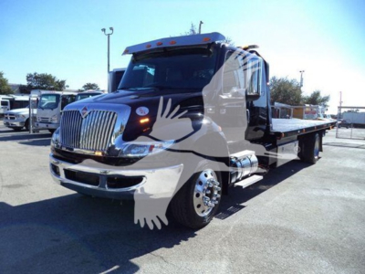 Truck with black and white two-tone paint, International MV rollback truck, chrome grille, round headlights, flatbed. Visible text not legible; no other labels.