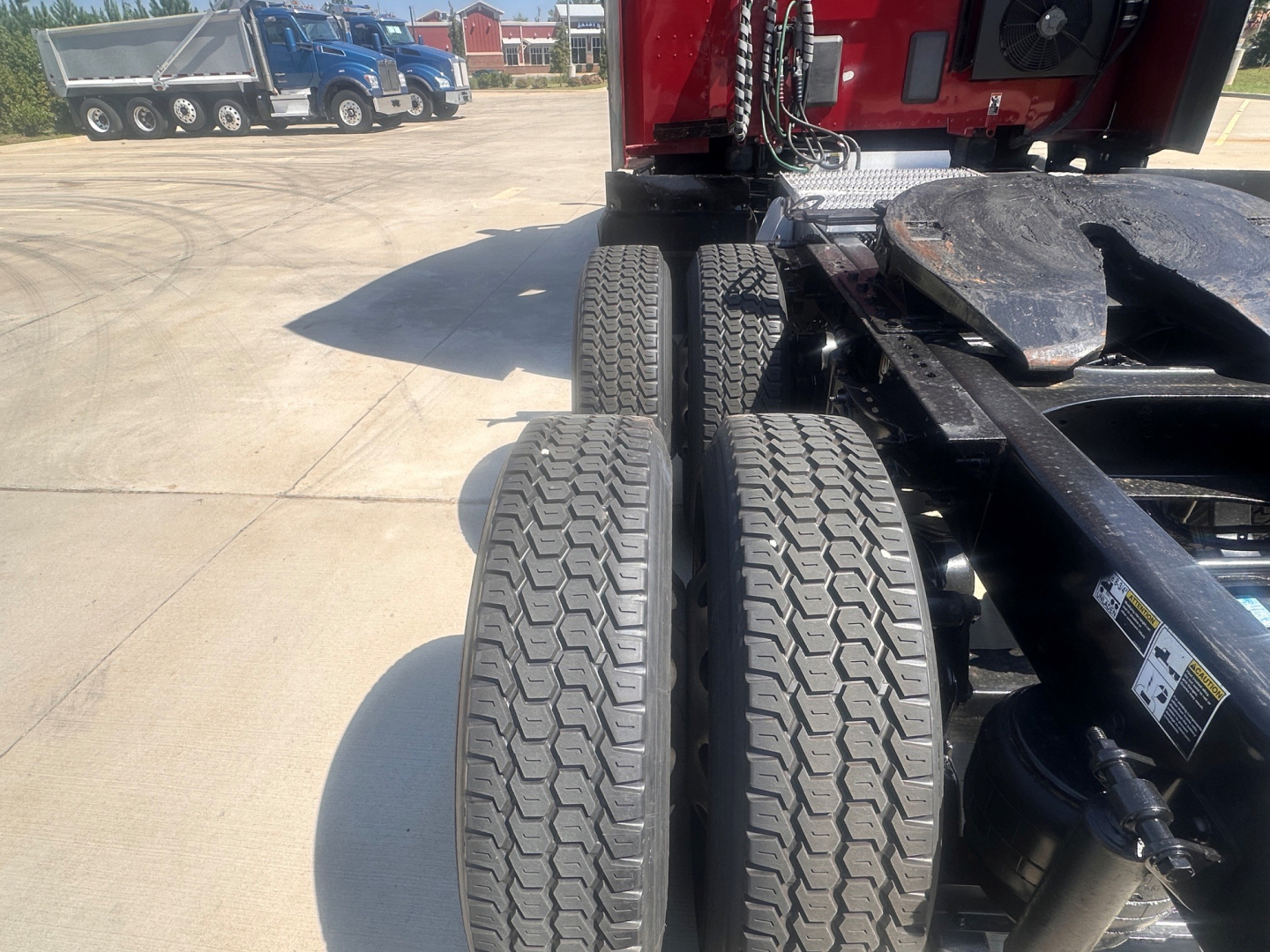Peterbilt 579 chassis and dual rear axles with tires visible in foreground and red cab in background.