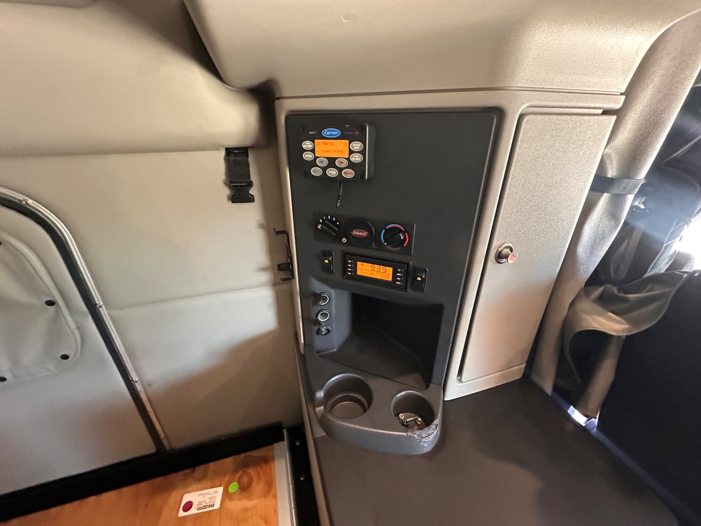 Panel in Peterbilt 579 interior shows control keypad and radio unit with circular climate controls, storage cubbies, and cupholders.