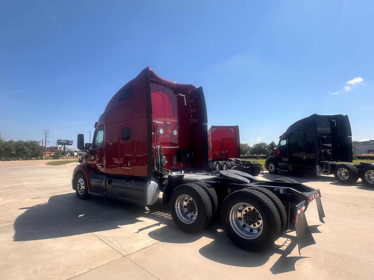 Peterbilt 579 truck tractor side view showing rear quad-axle configuration and red cab in a parking lot.