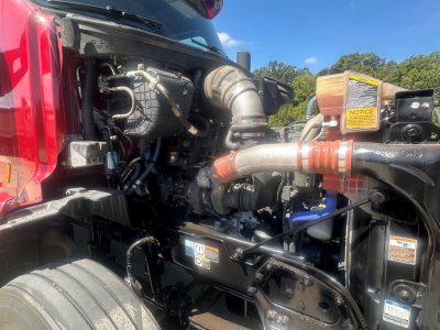 Peterbilt 579 engine bay with hoses and components visible; turbocharger intake and various labels on yellow warning stickers.