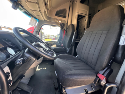 Interior of a 2021 Peterbilt 579 cab showing steering wheel, driver seat, and passenger seat with dashboard in view.
