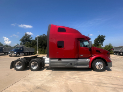 Peterbilt 579 tractor-trailer side view in red cab with sleeper, six wheels at rear on lot.