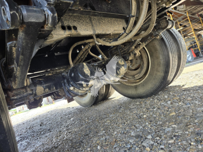 Viking steel flatbed trailer undercarriage showing wheel, suspension, and hydraulic lines; dirt and gravel beneath.