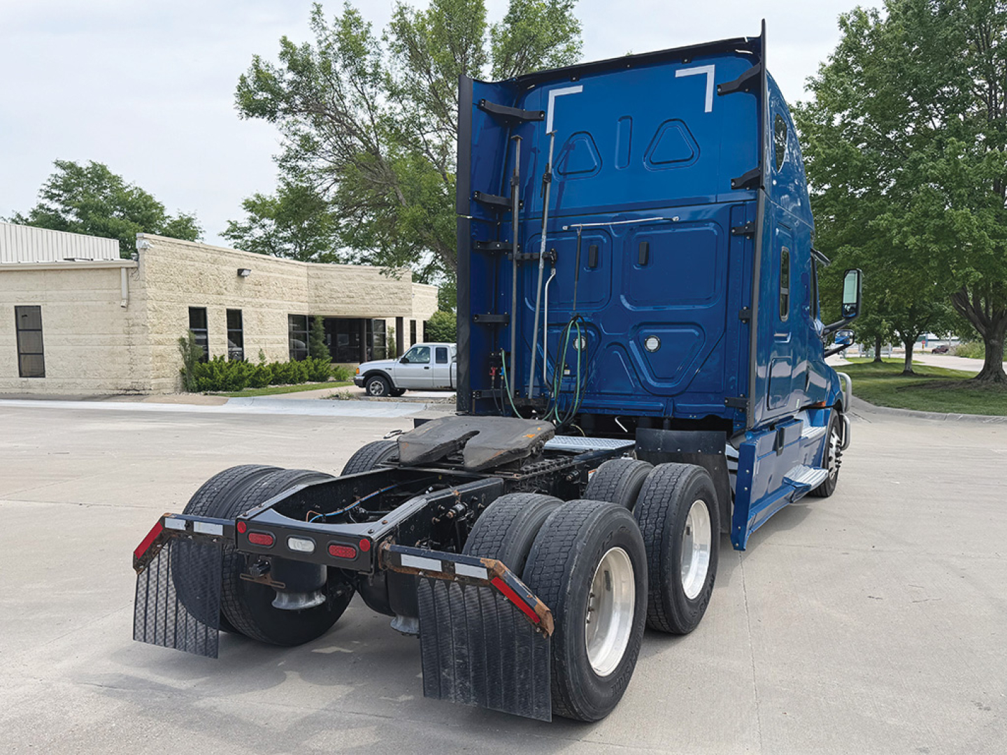 Freightliner Cascadia126 truck tractor from rear/side view showing tandem rear axles and blue sleeper cab.