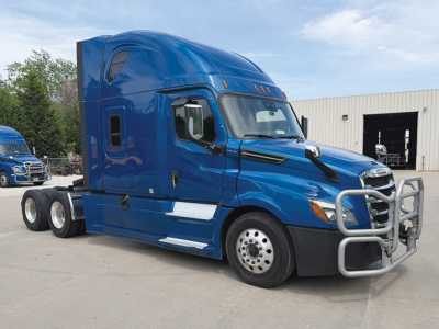 Truck cab showing a blue 2021 Freightliner Cascadia 126 sleeper with stacked exhaust, man door, chrome bumper guard, and three axles at rear; VIN MSMS7143 visible in listing context.