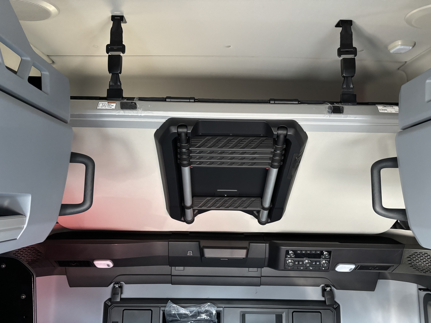 CAB interior showing overhead storage and sleeper area with ventilation and control panel; central console area visible.