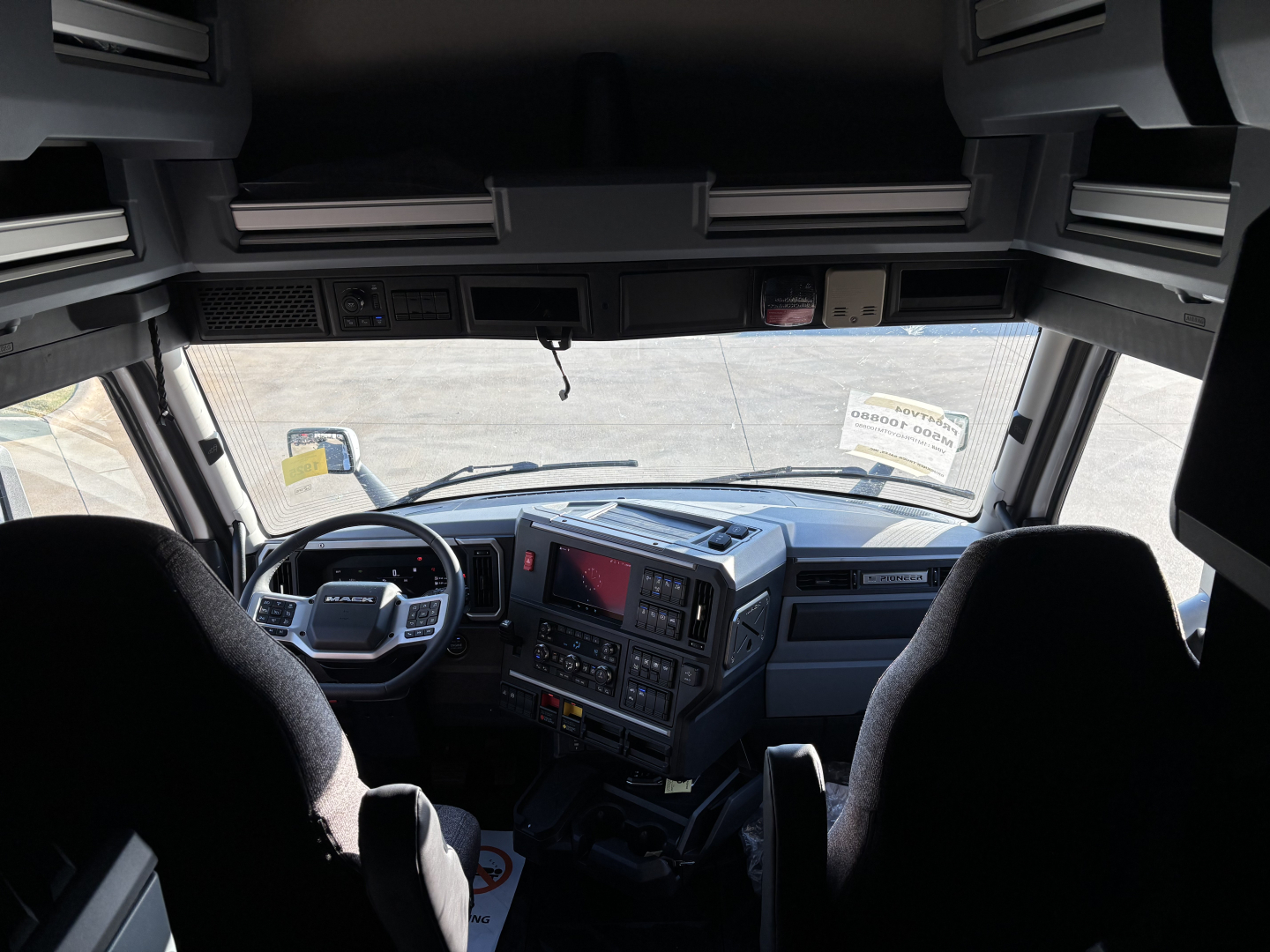 Cab interior of a new 2026 Mack PR64T76H truck showing dashboard with steering wheel, center console, and two front seats.