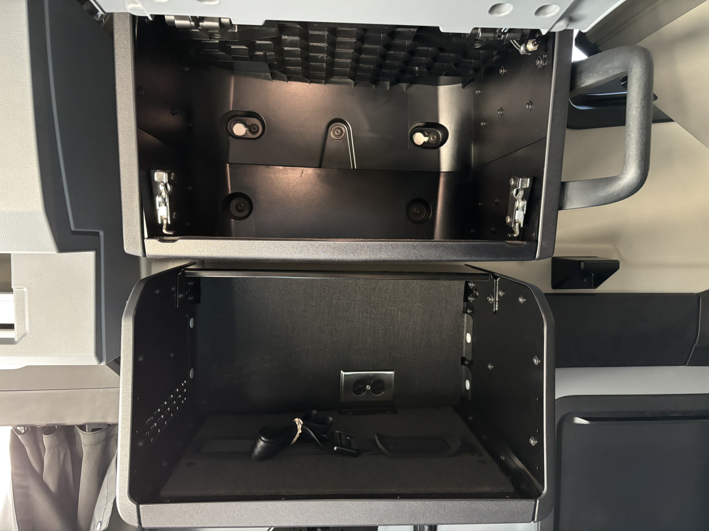 Truck cab storage area open showing compartments and mounting hardware inside with keys.