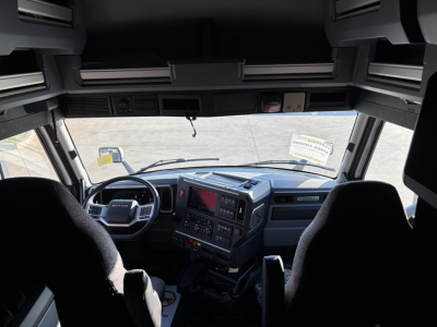 Cab interior of a new 2026 Mack PR64T76H truck showing dashboard with steering wheel, center console, and two front seats.
