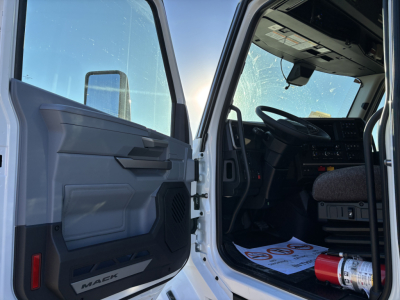 Truck cab interior and open door of a Mack PR64T76H with steering wheel and dashboard visible