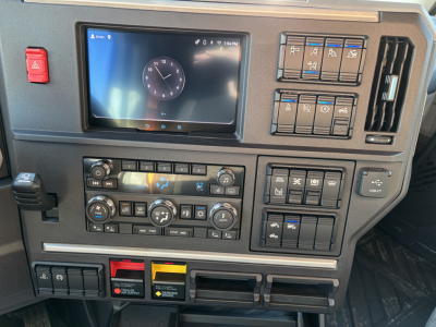 Mack PR64T76H dash panel showing infotainment display, climate controls, switches, and storage compartments.