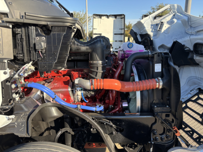 Mack PR64T76H engine bay with red engine block, blue coolant line, and orange high-pressure hose in view.