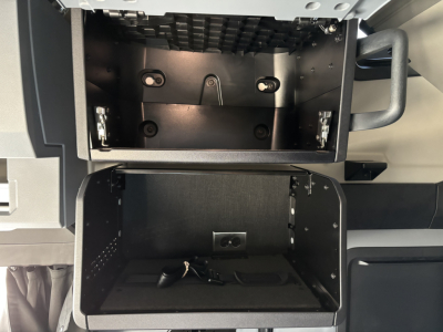 Truck cab storage area open showing compartments and mounting hardware inside with keys.