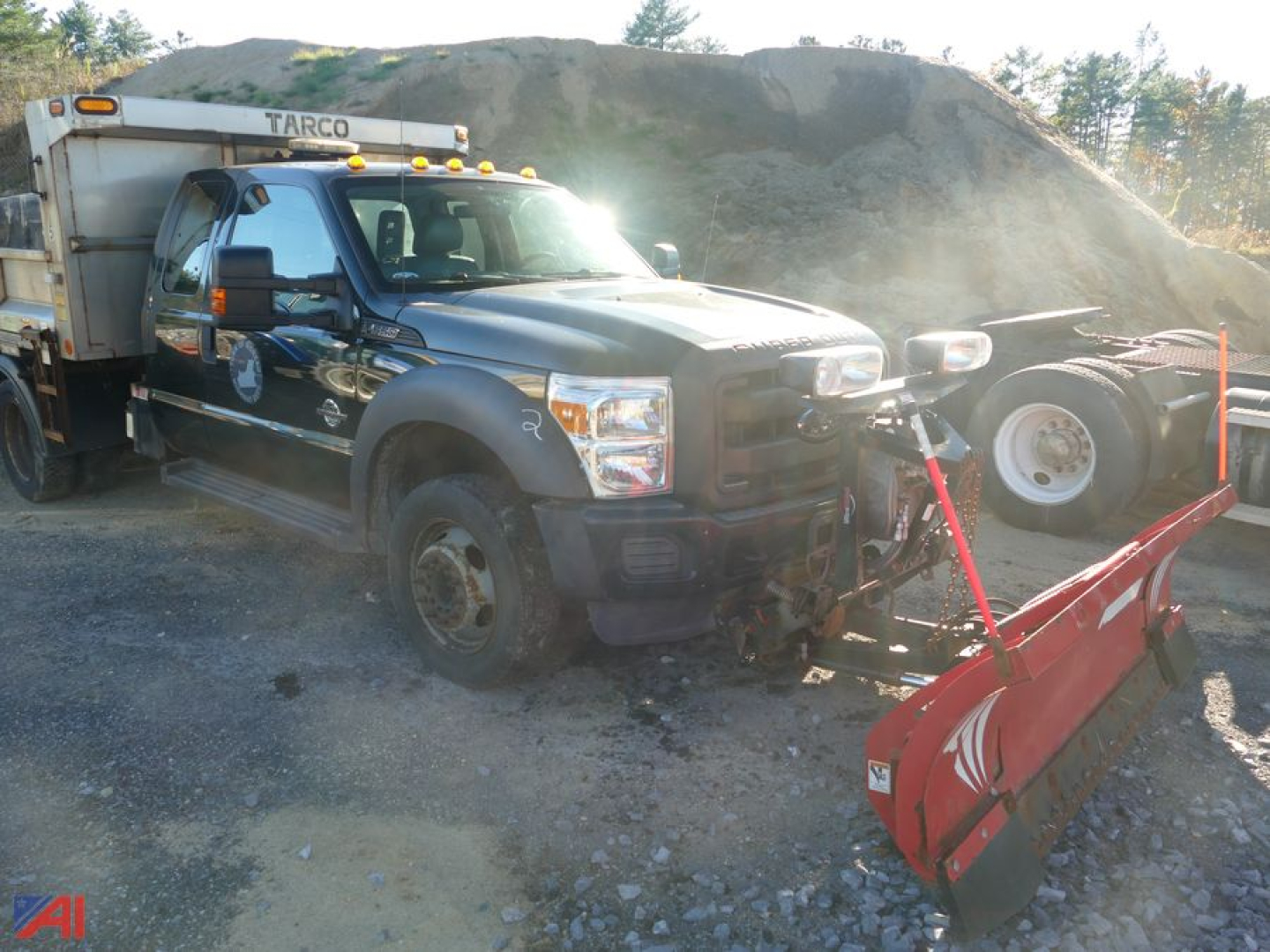 Ford F-550 Super Duty dump truck with plow attachment and Tarco snow plow blade, front view on a construction site.