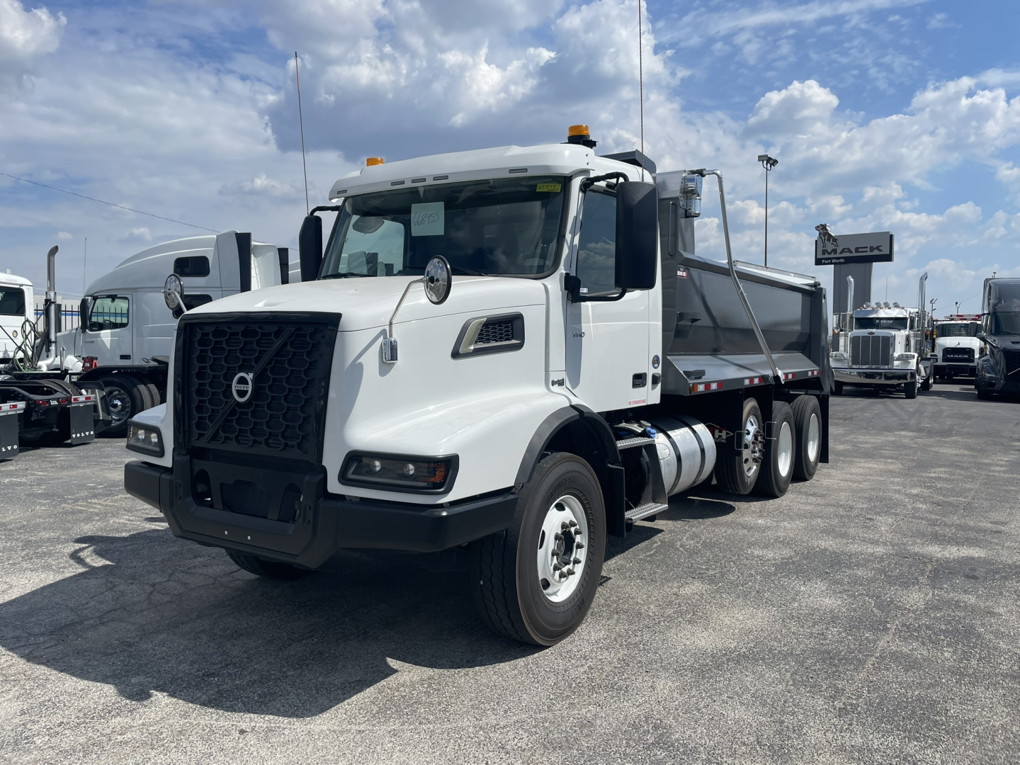Volvo VHD86B300 dump truck showcased from front-left view with white cab, black grille, and dual rear axles; stock and VIN not visible on text; outdoor lot.