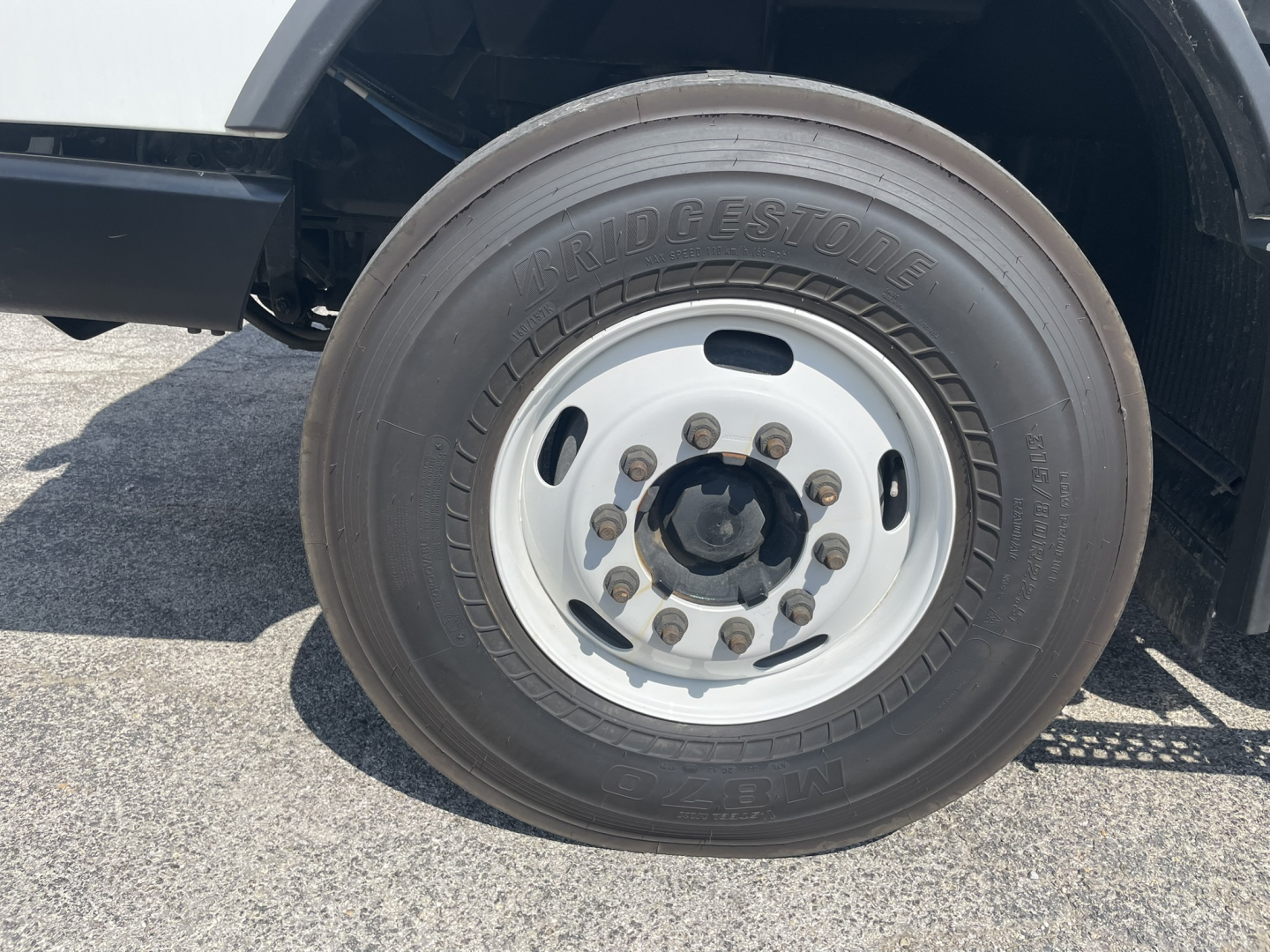 Bridgestone tire mounted on a Volvo VHD wheel with lug nuts and white steel rim; part of the truck’s front wheel area.