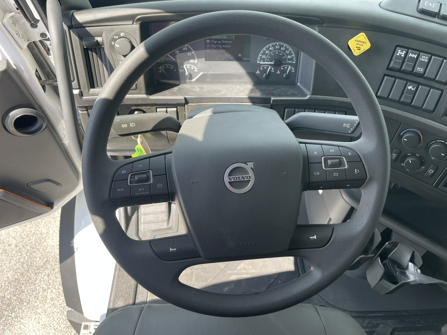 Volvo steering wheel and dashboard inside a 2025 Volvo VHD86B300 dump truck cab showing instrument panel and steering wheel controls.