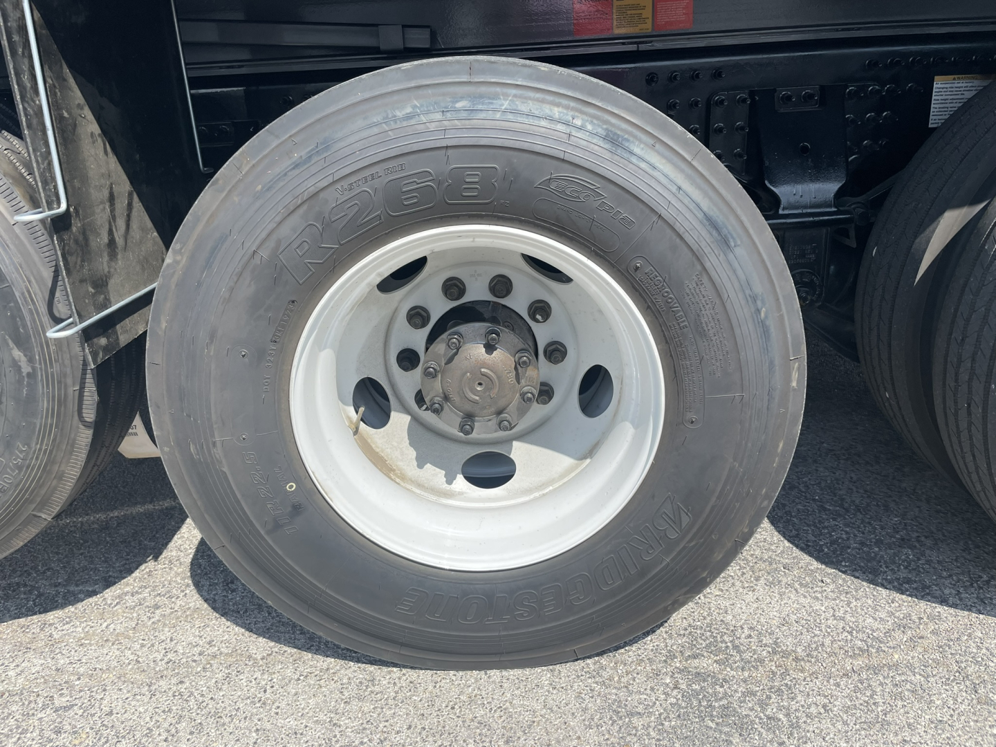 Wheel and tire assembly of a Volvo truck showing the tire sidewall with embossed numbers and wheel hub, part of a dump truck chassis.