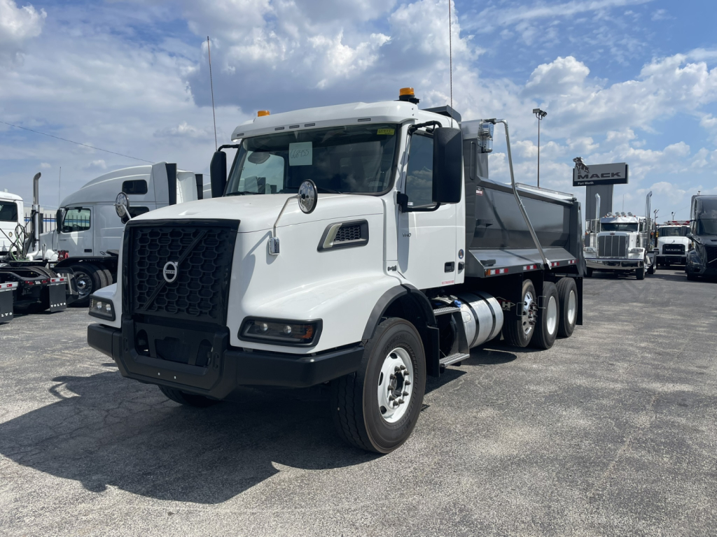 Volvo VHD86B300 dump truck showcased from front-left view with white cab, black grille, and dual rear axles; stock and VIN not visible on text; outdoor lot.