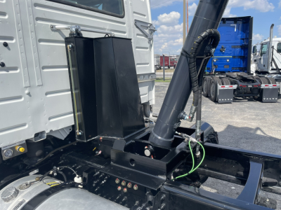 Truck chassis with hydraulic arm and black metal components; visible labels on chrome and painted surfaces; no legible text beyond small label near fittings.