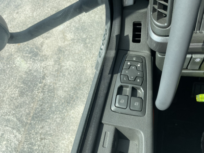Volvo interior showing door mirror controls with window/lock switches and steering column; part of instrument panel visible.