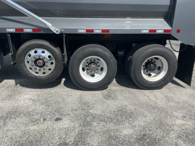 Three rear axles of a Volvo dump truck with wheels and tire rims visible. No legible labels or numeric markings readable on the tires themselves in the image.