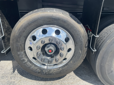 Wheel and tire close-up on a yellow Volvo VHD86B300 dump truck showing chrome rim with lug nuts and tire with AS something marking.