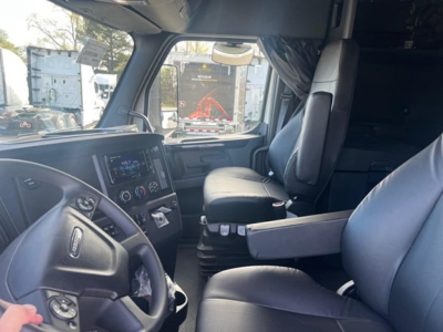Freightliner Cascadia 126 truck cabin interior view showing steering wheel, dashboard touchscreen, and captain seats.