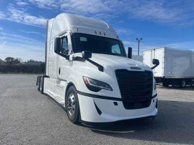 Freightliner Cascadia 126 truck front-right view with white paint and black grille, in a lot.