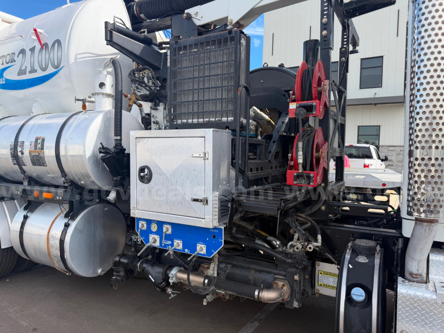 Truck rear/side view of a 2016 Kenworth T470 Vactor vacuum truck showing a large white tank, metal framework, and hydraulic/mechanical components with red wheels and control boxes.