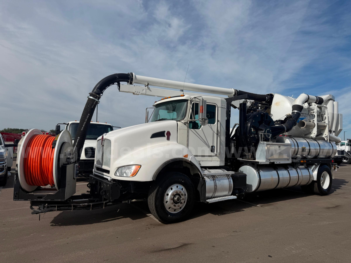 Kenworth T470 vacuum truck with Vactor apparatus, white cab, large hose reel on front left, truck-mounted vacuum system and tanks visible.