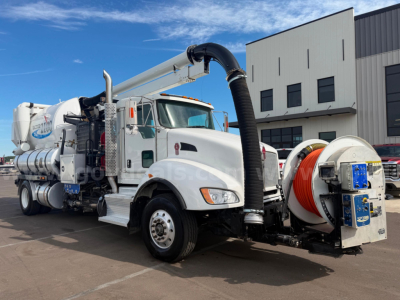 Kenworth T470 vacuum truck with Vactor hose reel and vacuum unit, white cab, orange hose, front hood shows Kenworth emblem.