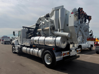 Kenworth T470 Vactor vacuum truck with large mounted vacuum system and hoses visible from rear three-quarter view.