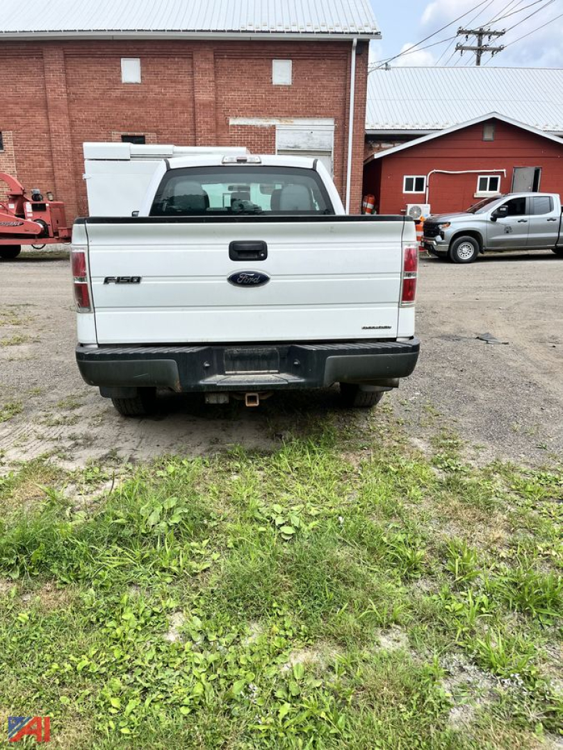 Ford F-150 tailgate view showing 3.5L badge and rear bumper with hitch in a used pickup truck lot.