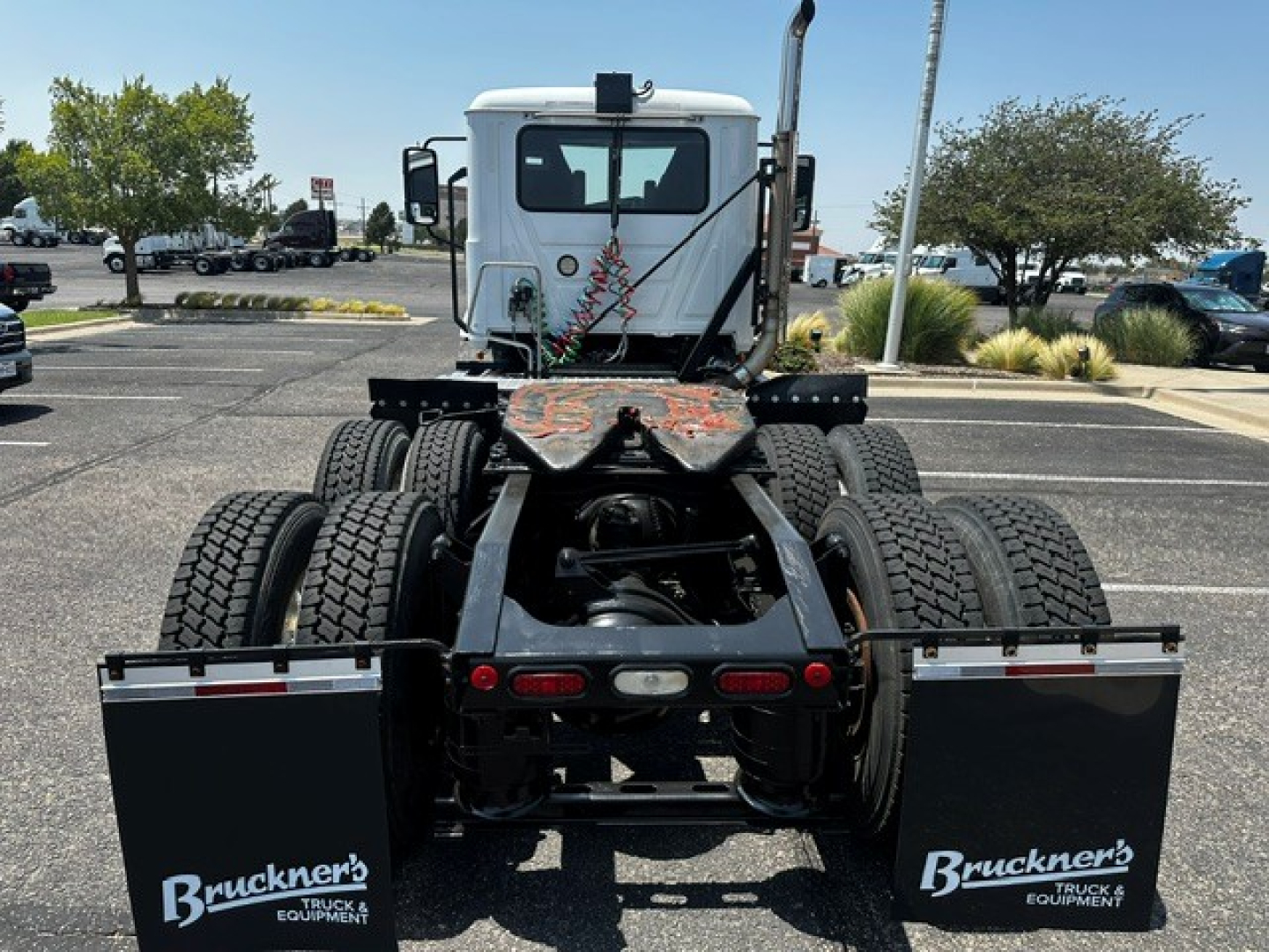 Truck chassis rear view showing dual rear axles and fifth wheel mounting with Bruckner's Truck Equipment branding on mud flaps.