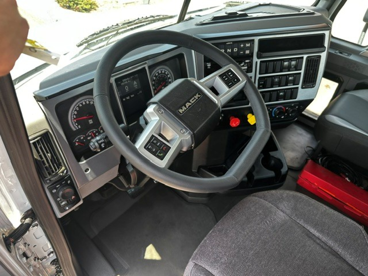 Trucking dash and steering wheel view in a Mack Anthem cab showing instrument cluster and control panel.