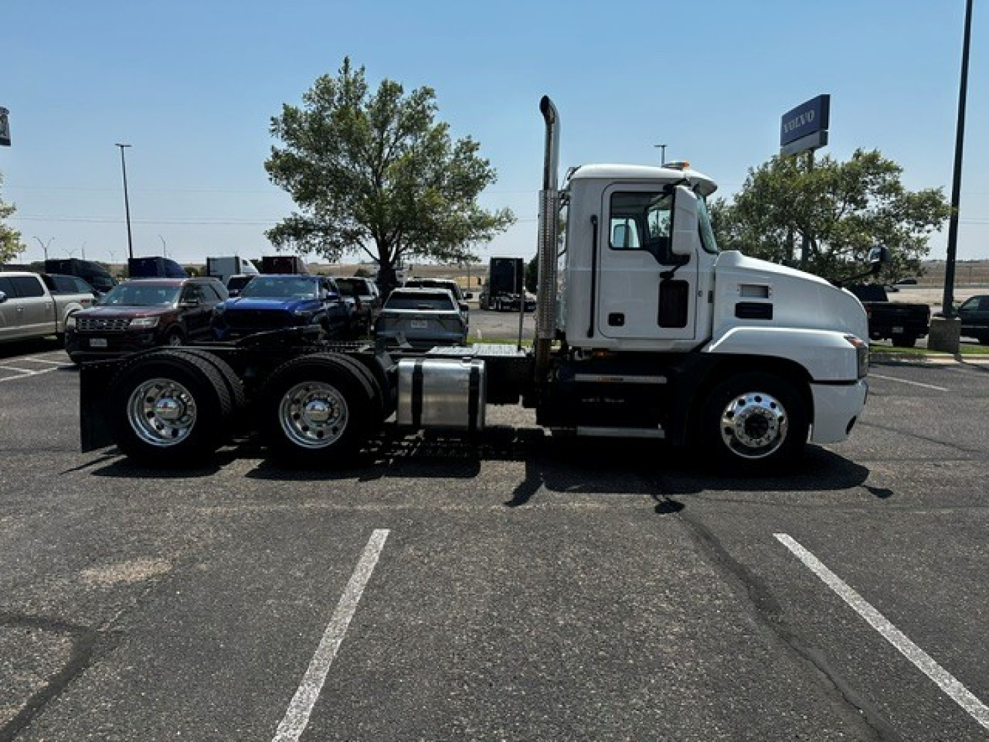 Mack ANTHEM truck tractor side view showing white long nose cab and dual rear axles in a parking lot.