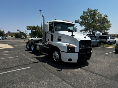Truck front-left view of a white 2021 Mack Anthem daycab with dual rear axles and black grille, in a parking lot.