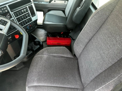 Truck cab interior of a 2021 Mack Anthem showing driver seat, passenger seat, steering wheel, center console, and dashboard with control panel.