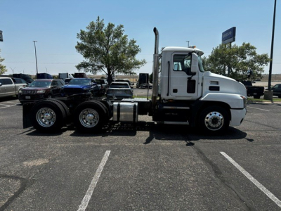 Mack ANTHEM truck tractor side view showing white long nose cab and dual rear axles in a parking lot.