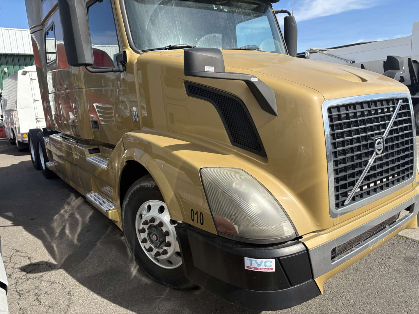 Front-left view of a gold Volvo 770 tractor with large grille, headlights, and bumper. Visible text includes numbers '010' on the fender and a rectangular IVC sticker on the bumper.