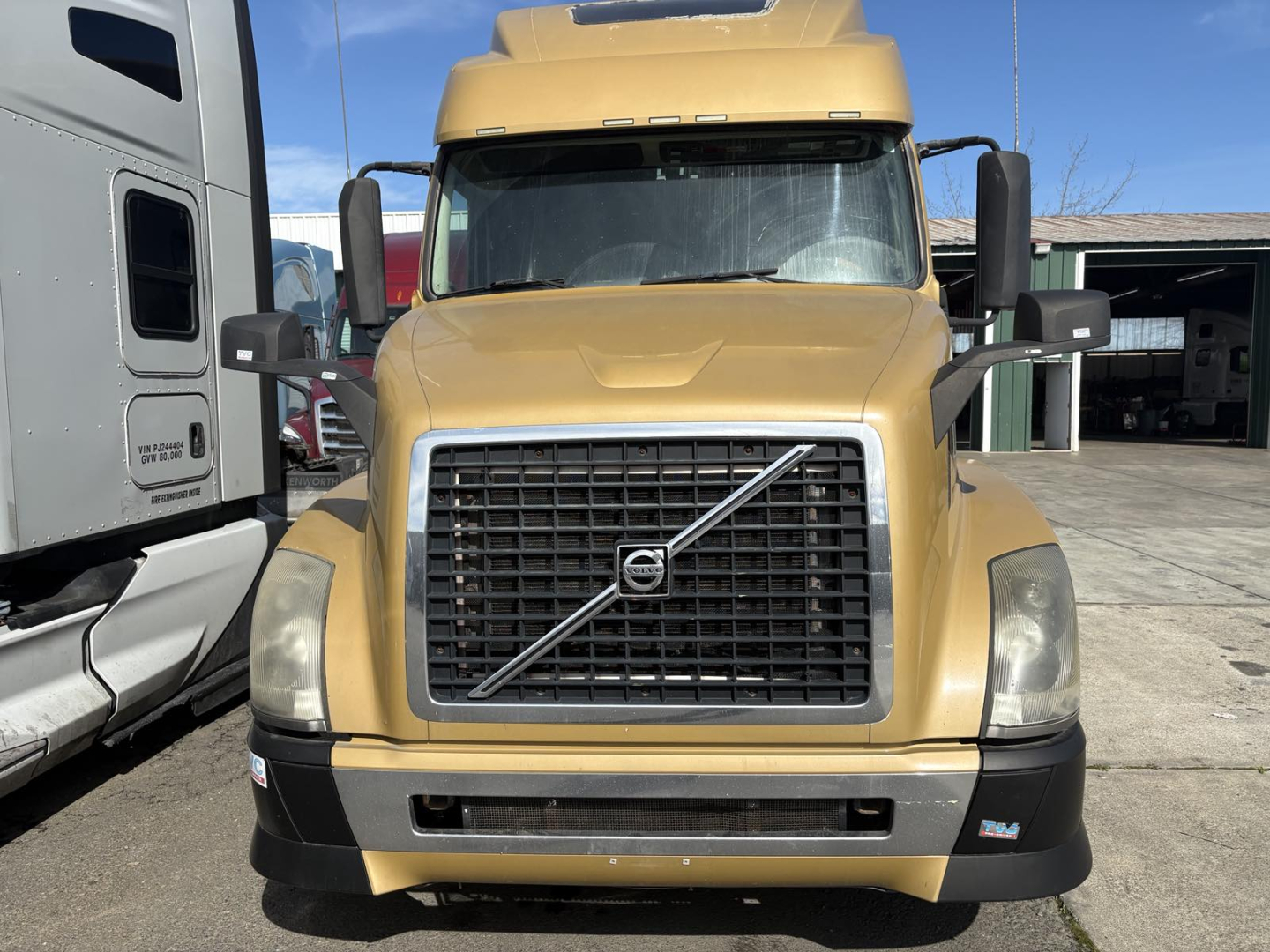 Volvo 770 conventional sleeper truck front view showing gold paint, large black grille with Volvo emblem, rectangular headlights, and side mirrors.