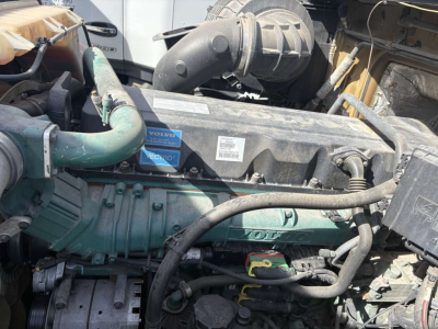 Volvo engine bay with visible coolant hoses, air intake, and engine labeling; components include green engine cover with Volvo branding and various hoses and wiring.