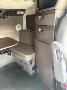 Cab interior of a Volvo 770 sleeper showing seating area, storage drawers, and entry from driver seat.