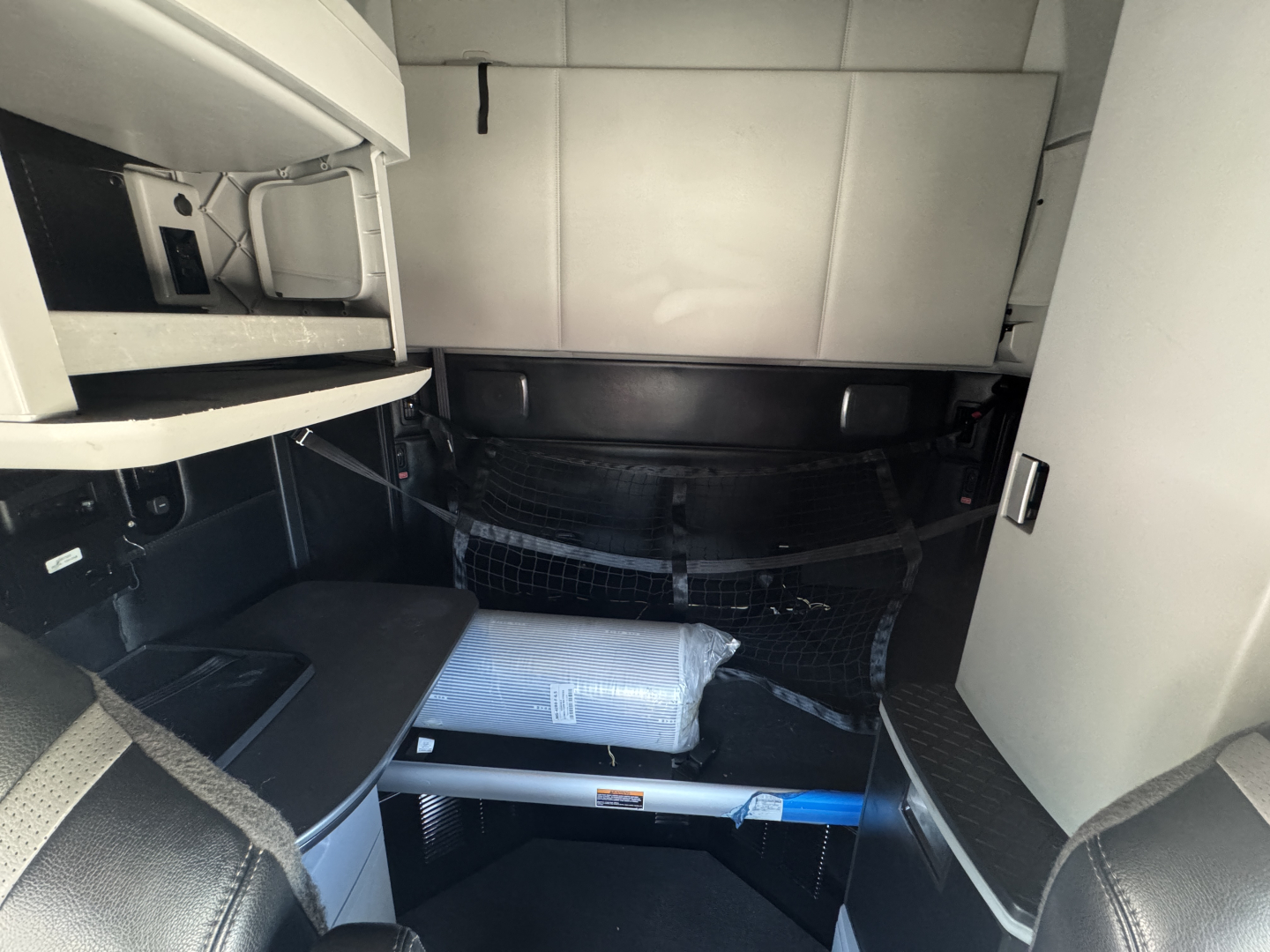 Kenworth T680 cabin interior showing sleeper storage and storage shelf in in-cab area.